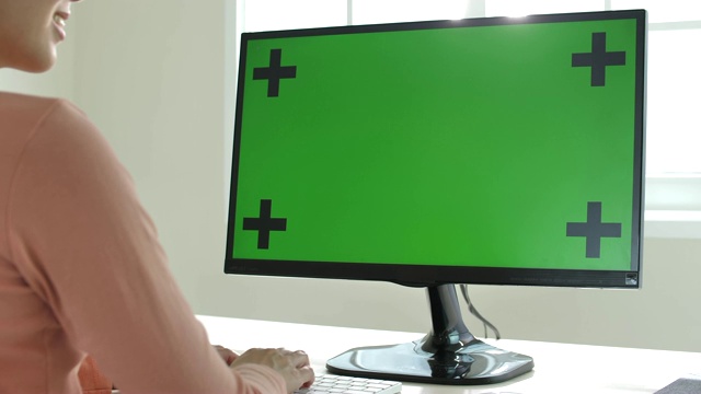 一位女士在用绿色屏幕的电脑视频下载