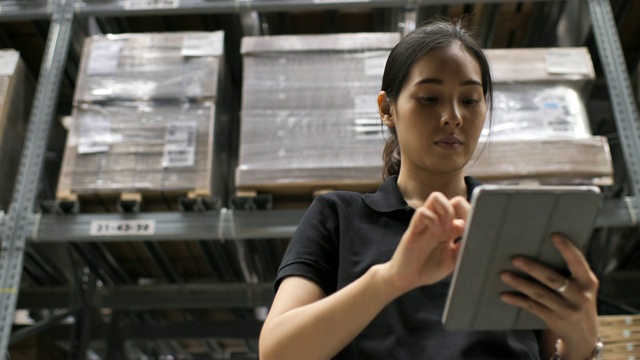 亚洲女工人在仓库用平板电脑检查物资视频下载