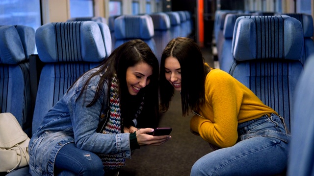 幾個女性朋友坐火車旅行，用智能手機看電視。視頻素材