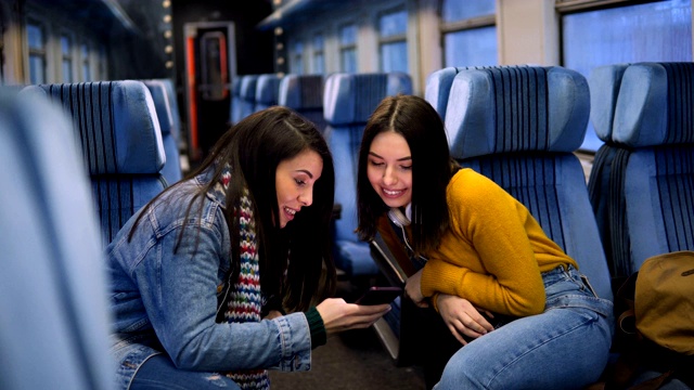 幾個女性朋友坐火車旅行，用智能手機看電視。視頻素材