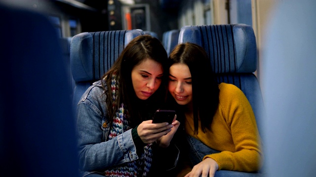 幾個女性朋友坐火車旅行，用智能手機看電視。視頻素材