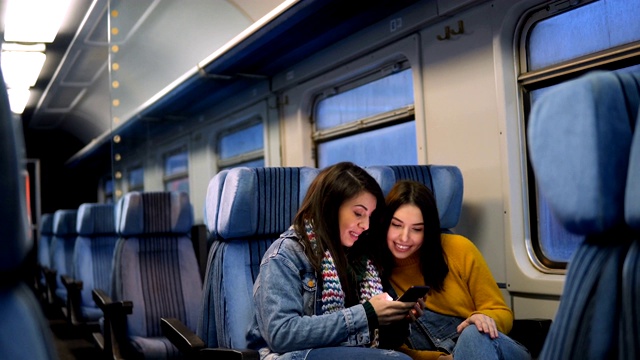 幾個女性朋友坐火車旅行，用智能手機看電視。視頻素材