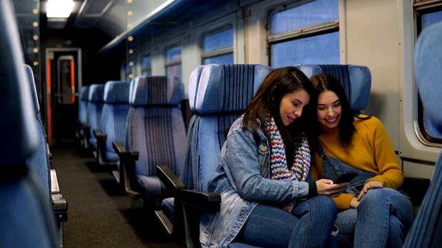 幾個女性朋友坐火車旅行，用智能手機看電視。視頻素材