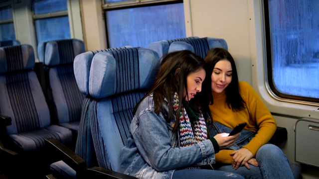 幾個女性朋友坐火車旅行，用智能手機看電視。視頻素材
