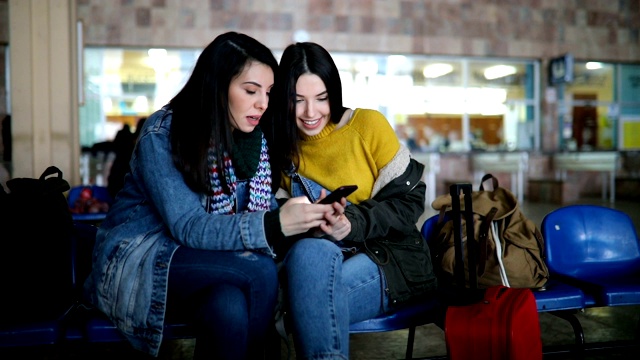 一對女性朋友在等火車的時候看手機視頻素材
