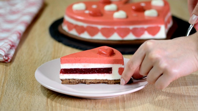 一块红莓慕斯蛋糕放在盘子里。美丽的装饰心形慕斯蛋糕，在情人节。视频下载