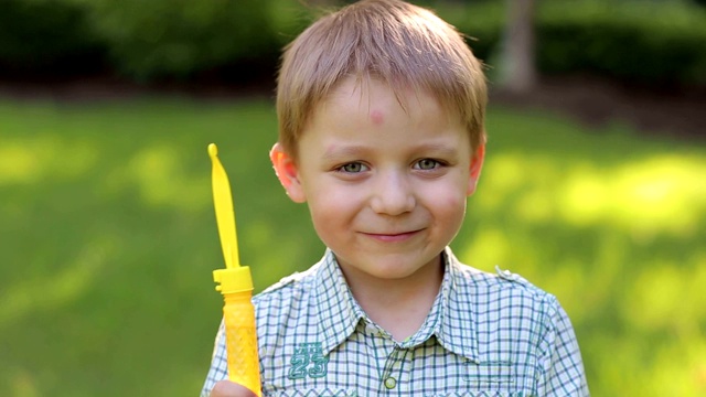 一个被蚊子叮咬的可爱小男孩在夏天玩肥皂泡。视频下载
