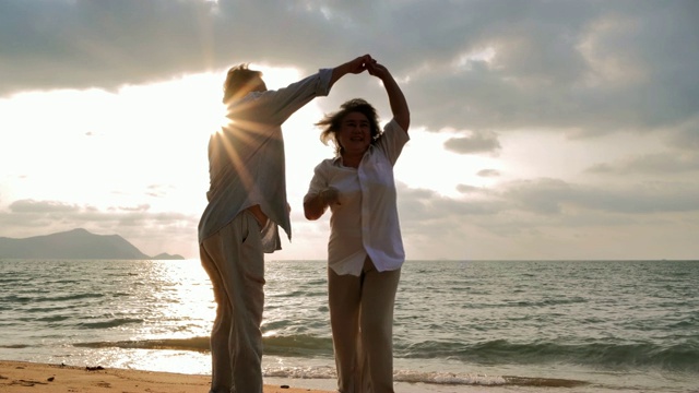 一对高年级情侣在阳光明媚的日子里在沙滩上跳舞，一对高年级情侣在海边放松。高级假期,假期视频下载