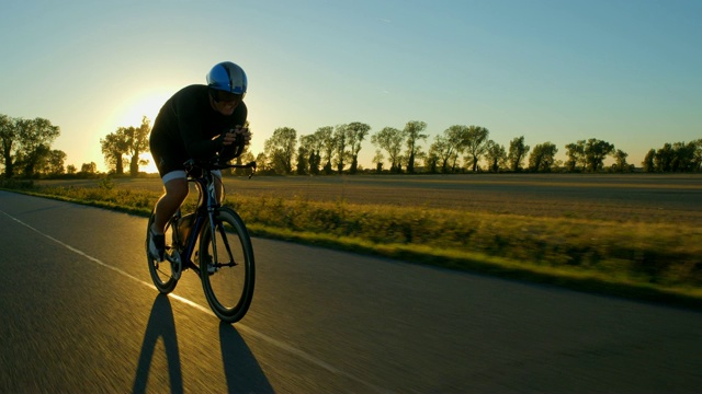 日落/日出时，一个骑自行车的人沿路使劲地叫卖。视频下载