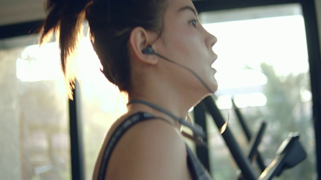 年轻女子在健身房的跑步机上锻炼和慢跑视频素材