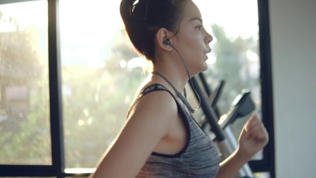 年轻女子在健身房的跑步机上锻炼和慢跑视频素材