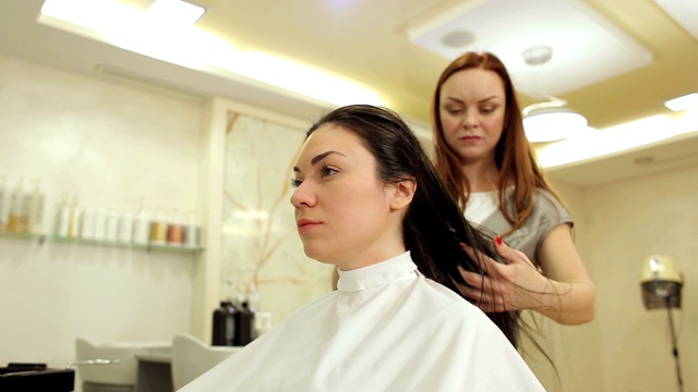 美容师在美容院为女士做新发型后吹干头发。视频素材