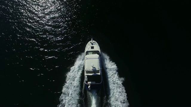 航拍图:阳光明媚的一天，白色摩托艇驶过黑湖视频素材