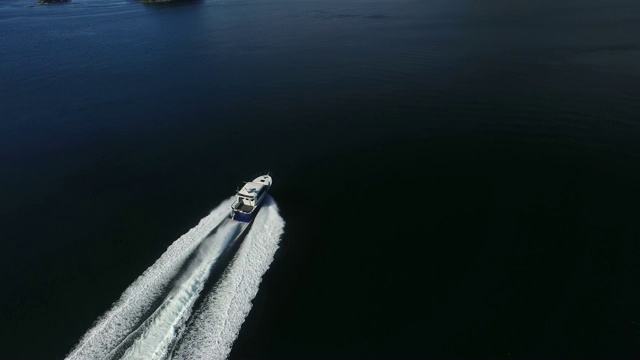 航拍:白色摩托艇驶过湖面，后面是白色波浪视频素材