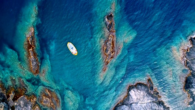 鸟瞰图上的一艘船在Cap De Creus海湾在西班牙。美丽的风景岩石和清澈的地中海绿松石水。夏日美景尽收眼底。视频下载
