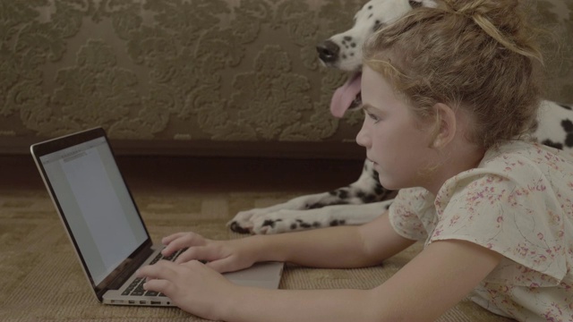 可爱的女孩在家里用达尔马提亚的笔记本电脑视频素材