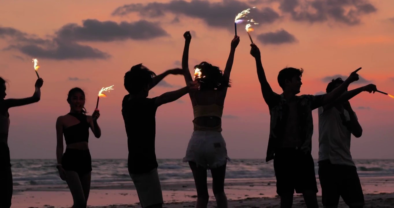 一群朋友的剪影在海滩上玩烟花视频素材