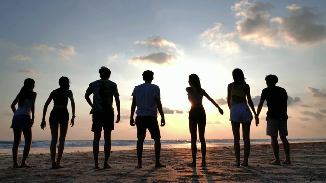 一群微笑的朋友在夏天的海滩上一起跳的剪影，友谊，海，暑假，假期和人的概念，假期-股票视频下载