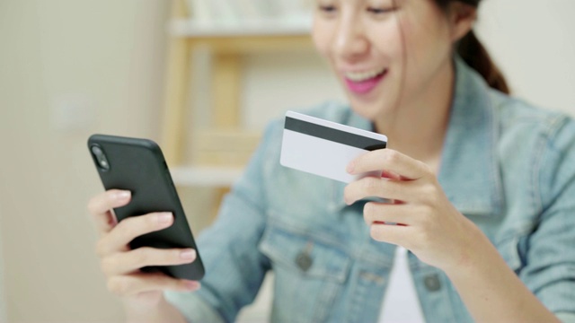 近手的迷人的亚洲女人使用信用卡支付手机视频素材