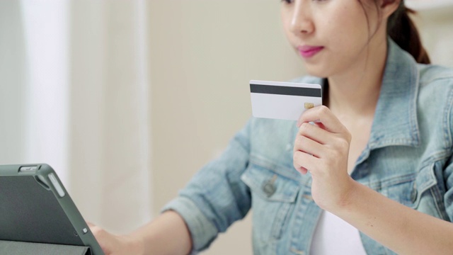 近距离接触手的迷人的亚洲女人使用信用卡支付平板电脑视频素材