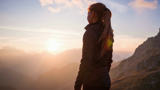 一個女人站在山頂，欣賞日落的美景視頻下載