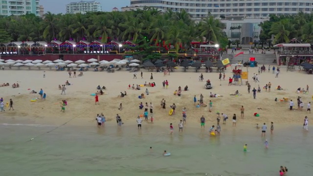 日落三亚著名的大东海拥挤的海滩航拍全景4k海南中国视频下载
