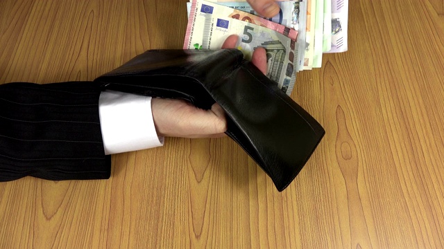 男子用手数黑色皮包里的欧元钞票。4 k视频下载