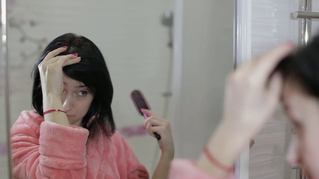 一名年轻女子在浴室对着镜子梳头视频素材
