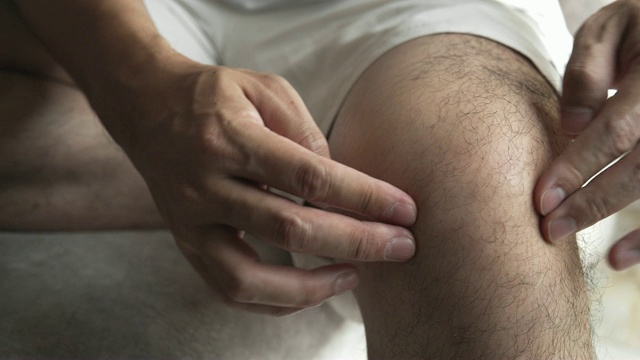 亚洲男人按摩他的膝盖疼痛和感觉不好视频素材