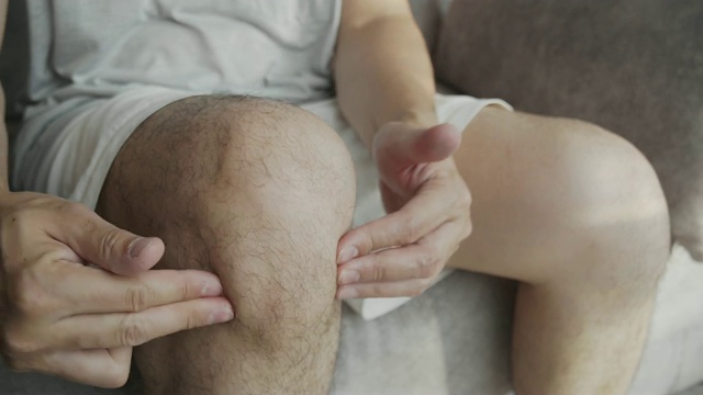 亚洲男人按摩他的膝盖疼痛和感觉不好视频素材
