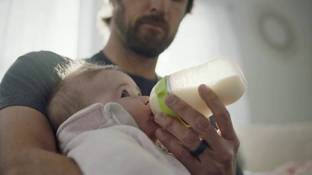 SLO MO:一位单身父亲用奶瓶喂他的孩子。视频下载