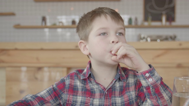 小男孩在咖啡馆里把薯条放进嘴里视频素材