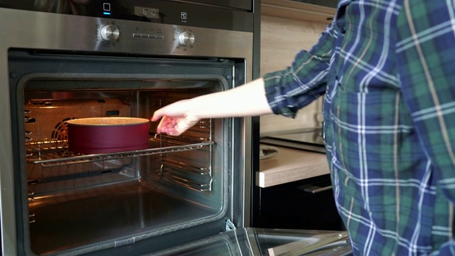 女人把蛋糕放进烤箱，并设置烤箱温度视频素材
