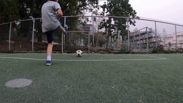 男孩正在绿地上踢足球视频下载