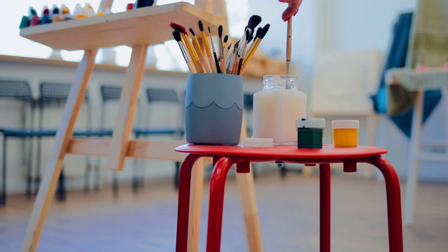 艺术家的工作场所。画笔、颜料和水在桌子上。照相机的圆周运动。视频素材