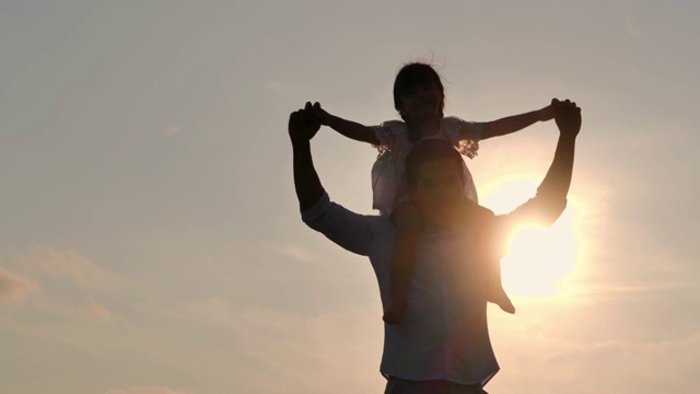 亞洲女嬰騎在父親的脖子上。爸爸和女兒在夏天一起在戶外玩。一家人在海灘上看日落。假日旅行的概念。假期——iStock視頻素材