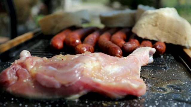 一个男人在为野餐的朋友准备烤鸡肉和香肠视频素材