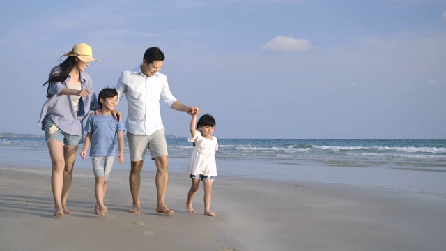 快乐的亚洲家庭享受和走在海滩上的暑假。缓慢的运动。家庭，假期和旅游的概念。视频购买