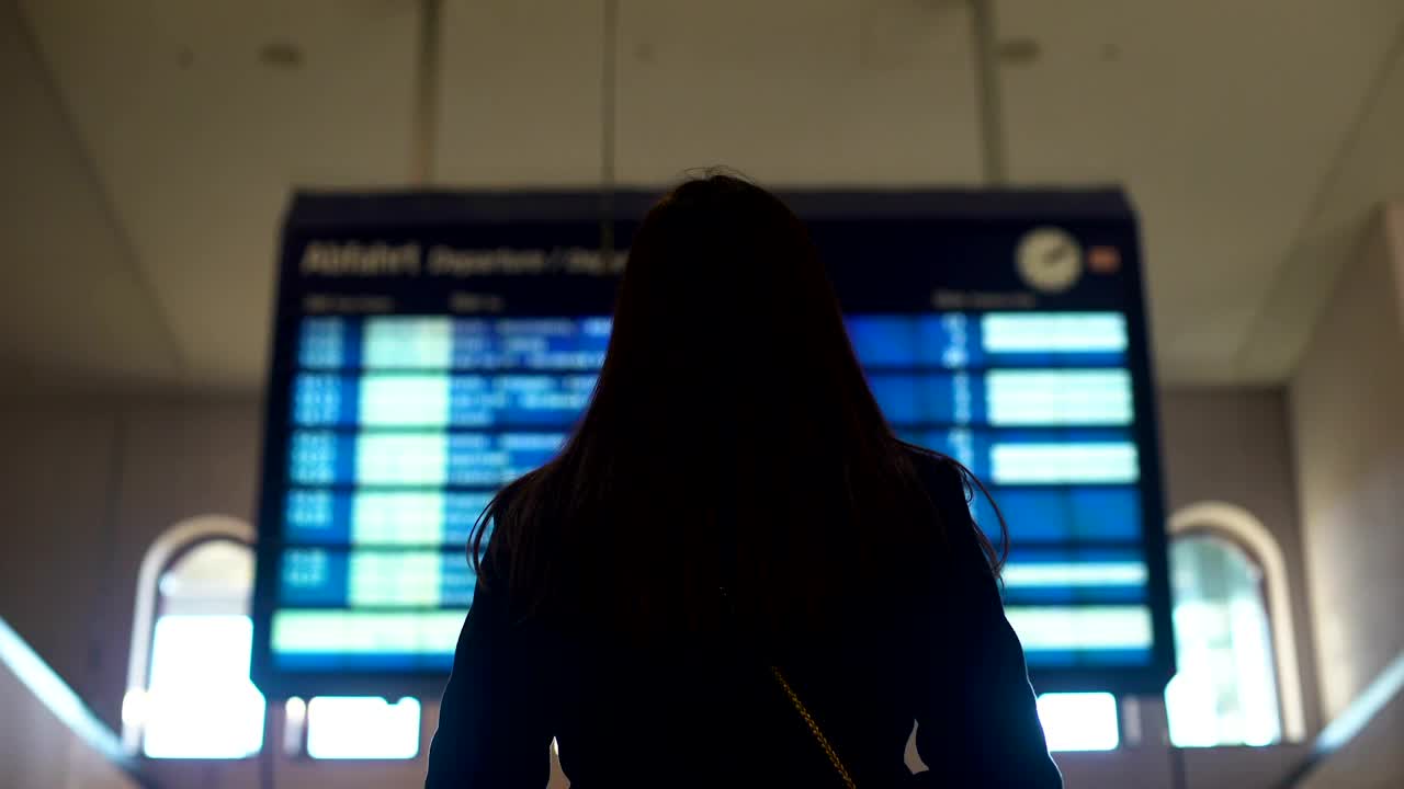 在火车站看时刻表的女士，计划旅行，等待火车视频下载