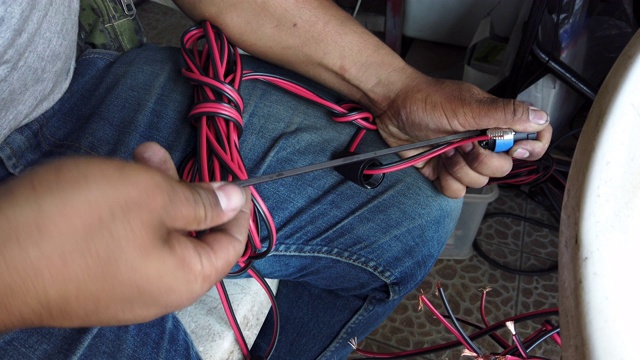 4K视频选择对焦中等拍摄的男人的双手使用螺丝刀使音频扬声器电缆与扬声器连接器。技术人员手工制作扬声器插线。视频下载