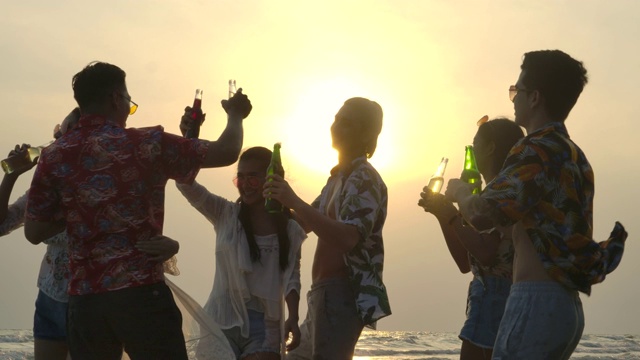 日落时分，一群年轻人在海滩聚会上跳舞的剪影。视频购买