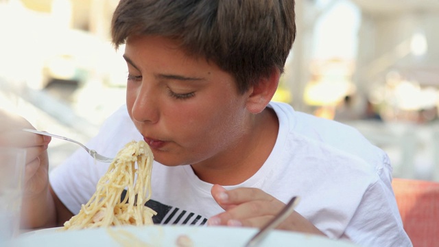 暑假，男孩在户外餐厅吃意大利面午餐视频素材