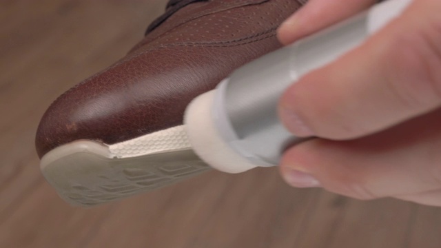 一位男士正在用涂膏器擦黑色休闲鞋。专业的鞋材护理产品视频素材