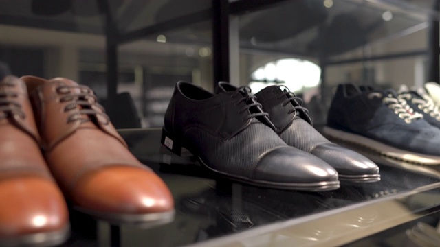 一名男性顾客在奢侈品商业时尚精品店中穿着经典风格的黑色皮鞋。上下相机拍摄视频下载