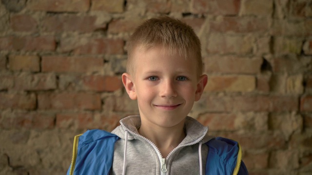 男孩站在砖墙附近。一个六岁小孩的肖像视频下载