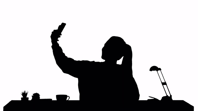 剪影美丽的女人自拍与她的手机坐在桌子上视频下载