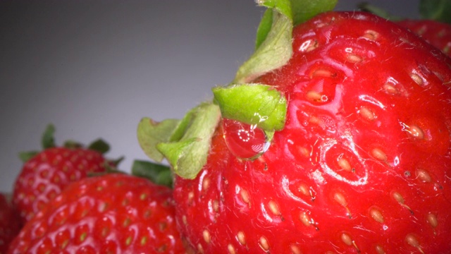 微距拍摄的红色多汁的草莓在黑暗的背景。甜浆果背景，健康的饮食方式视频下载