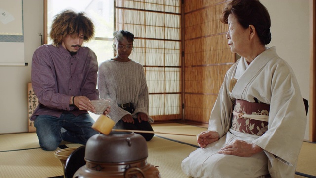 外国游客在日本传统仪式上观察女主人搅茶视频素材