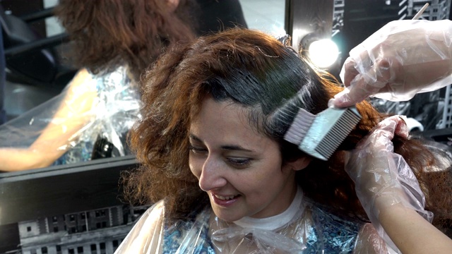 这个女孩的头发是在理发店里染的。理发师用画笔把她的头发刷了一下。关闭了。4 k。视频下载