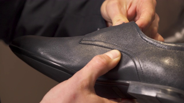 一个男性顾客在购买前检查黑色皮鞋质量的特写。商店和销售概念。视频素材